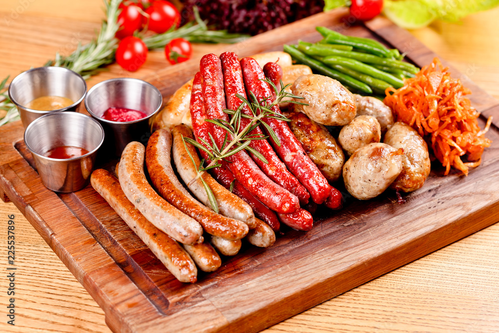 Oktoberfest food menu. Assorted grilled sausages, sauerkraut, green beans on wooden cutting board. Close up