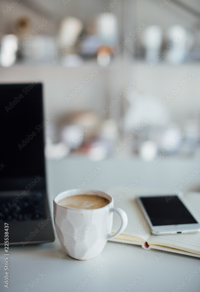 Fototapeta premium Modern white office, designer handmade cup with coffee, smartpho
