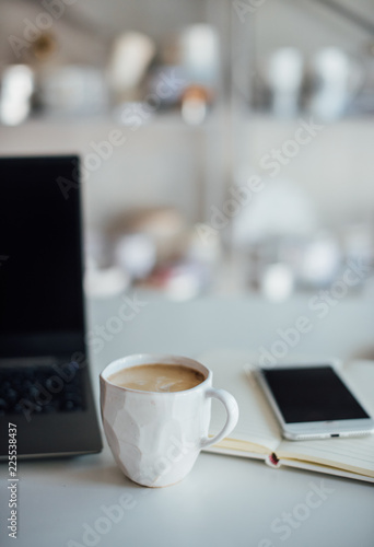 Modern white office, designer handmade cup with coffee, smartpho