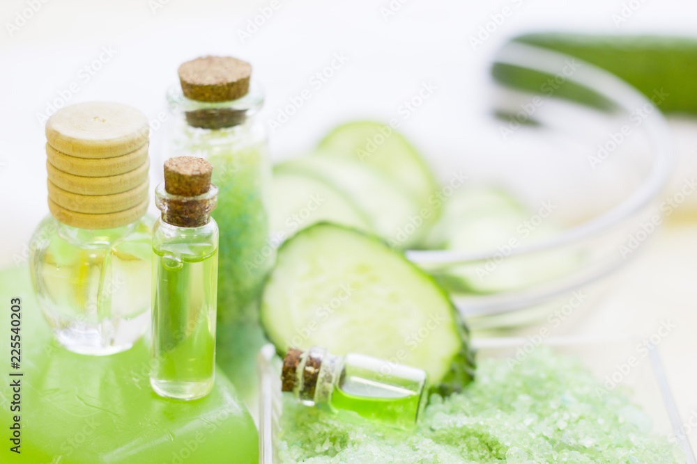 Cucumber home spa and hair care concept. Sliced cucumber, bottles of oil, soap, jar of mask, bathroom towel. White board background Cucumber home spa and hair care concept. Sliced cucumber, bottles of oil, soap, jar of mask, bathroom towel. White board background