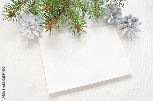 Empty white sheet of paper on a white Christmas background of fir branches and cones. Letter on xmas, mockup