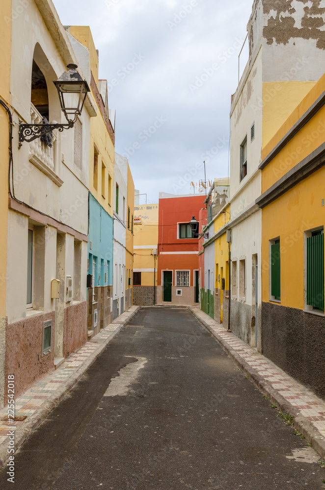 a narrow alley without people with coloured facades