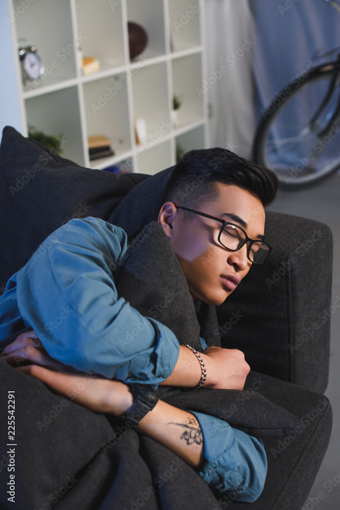handsome young asian man in eyeglasses sleeping on sofa at home