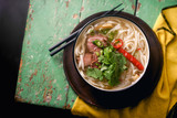 Vietnamese traditional soup Pho Bo with beef and fresh coriander on rustic wooden table