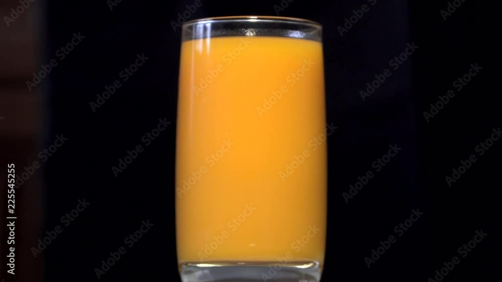 Pouring orange and yellow juice into a glass beaker. Behind the black background. A thin stream of juice is poured into a glass. Orange juice, pumpkin juice, mango juice, multifruit juice. 4K Pouring orange and yellow juice into a glass beaker. Behind the black background. A thin stream of juice is poured into a glass. Orange juice, pumpkin juice, mango juice, multifruit juice. 4K