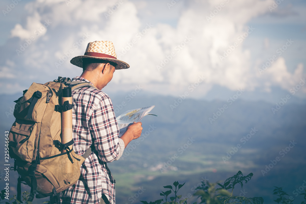 Young Man Traveler with map backpack relaxing outdoor with rocky mountains on background Summer vacations and Lifestyle hiking concept