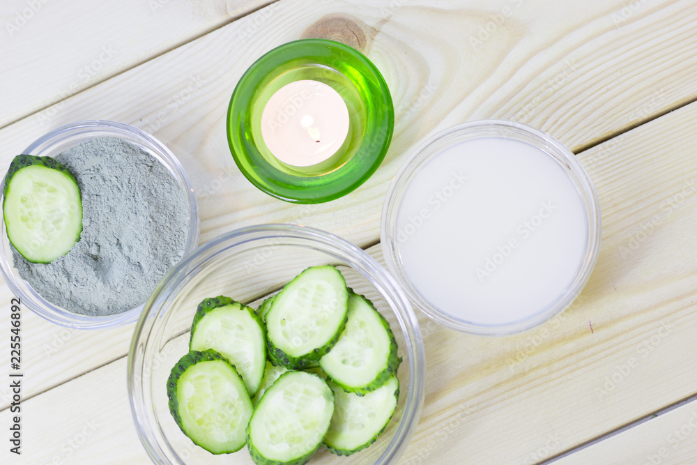 Cucumber home spa and hair care concept. Sliced cucumber, bottles of oil, sea salt, bathroom towel. White board background Cucumber home spa and hair care concept. Sliced cucumber, bottles of oil, sea salt, bathroom towel. White board background