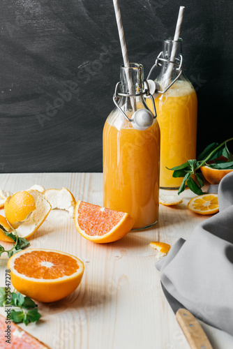 still life, orange juice in glass bottles on a wooden table with slices of sliced orange