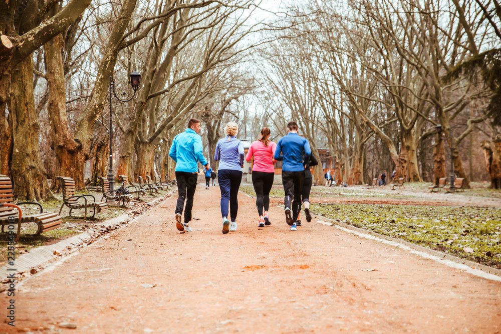 group of people running in city park in cold autumn day group of people running in city park in cold autumn day