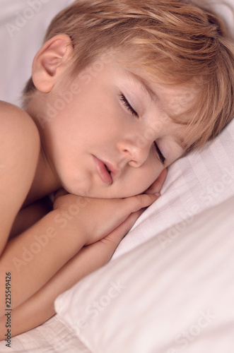 handsome european boy sleeps sweetly on the bed. The child is sleeping . The boy is sleeping