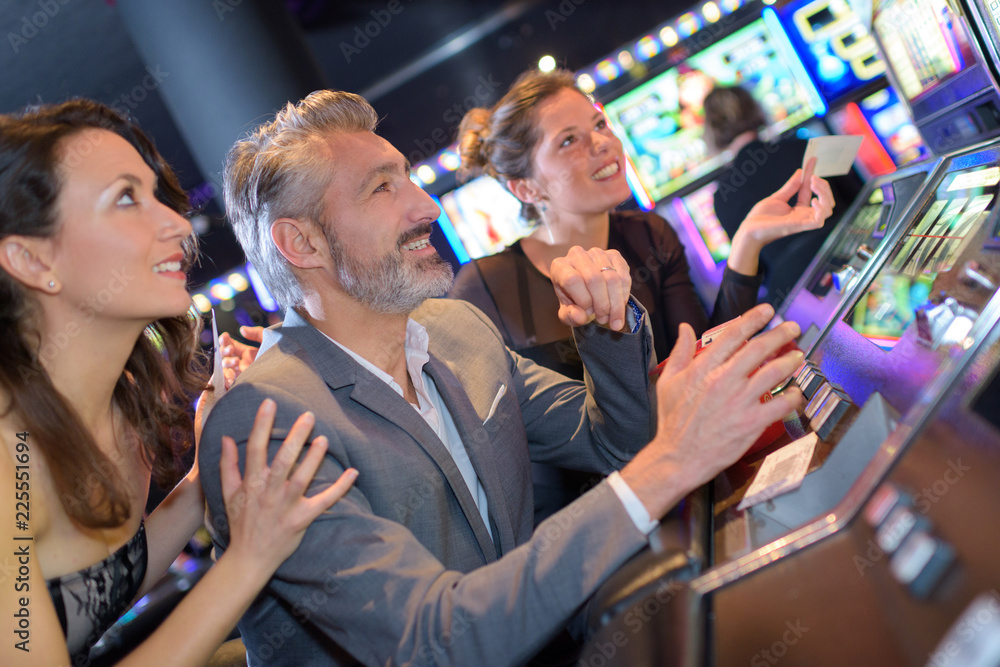 People in casino excitedly watching slot machine