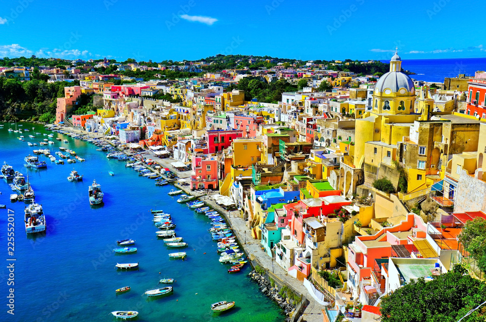 View of the Port of Corricella with lots of colorful houses on a sunny day in Procida Island, Italy.