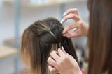 Selective focus of hands of hairdresser braiding spikelet to client in beauty salon