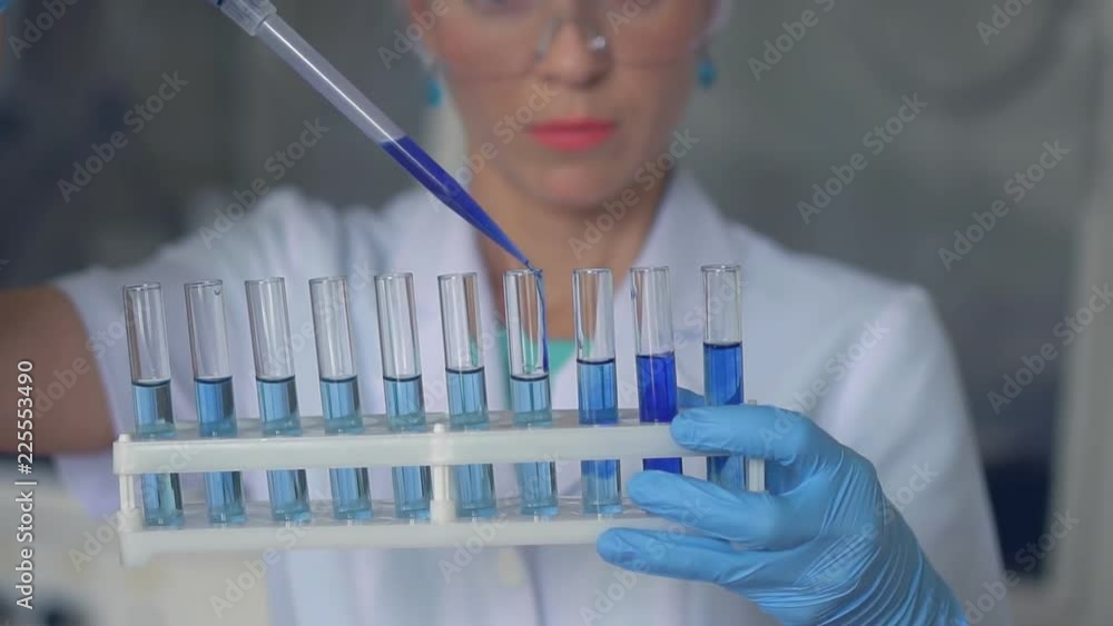 Scientist pouring blue liquid in test tubes in a laboratory. HD Scientist pouring blue liquid in test tubes in a laboratory. HD
