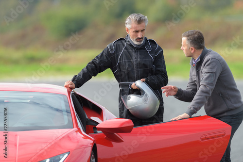 Картината върху платно 2 men on a race track talking near a ferrari