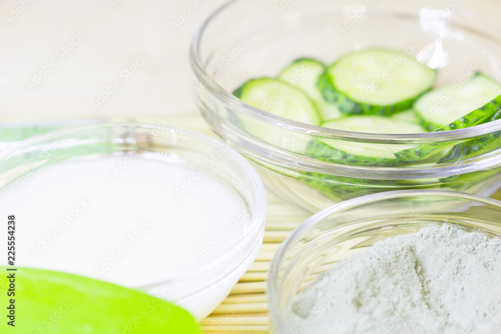 Cucumber home spa and hair care concept. Sliced cucumber, bottles of oil, bathroom towel. Straw light background Cucumber home spa and hair care concept. Sliced cucumber, bottles of oil, bathroom towel. Straw light background
