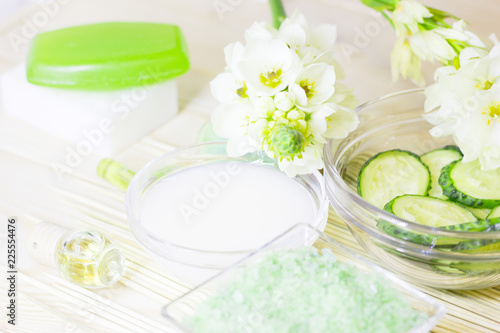 Cucumber home spa and hair care concept. Sliced cucumber, bottles of oil, sea salt, bathroom towel. Straw light background