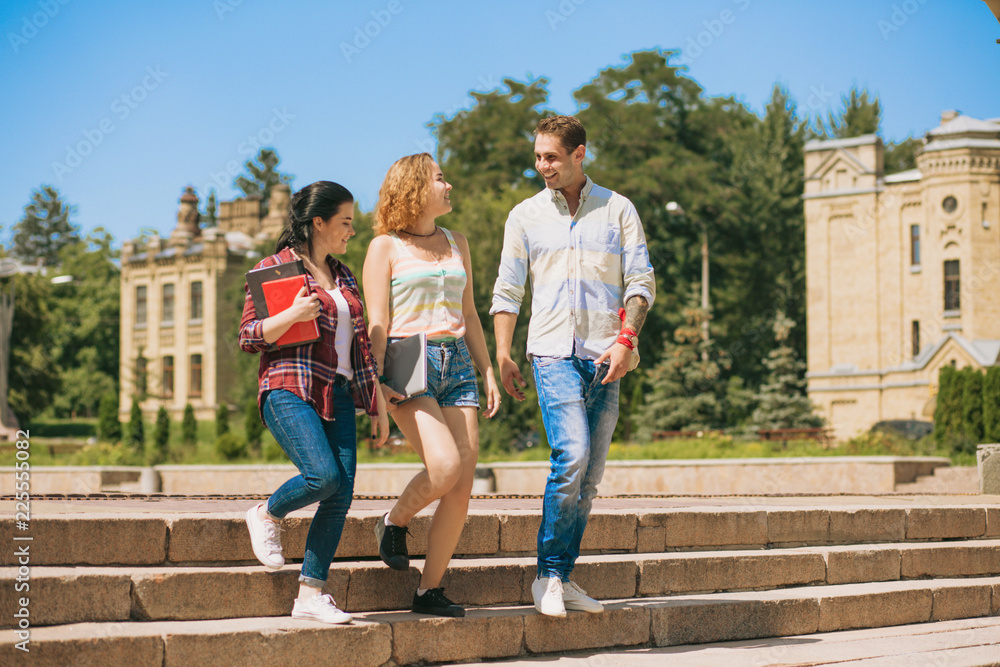 Cheerful girls and one man walking. Students are getting down the stairs in the campus. Cheerful girls and one man walking. Students are getting down the stairs in the campus.