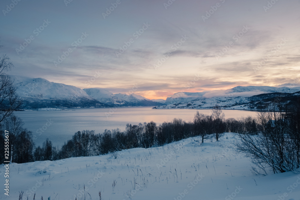 Landscape of Norway in winter at blue hour. Norwegian coastline in winter. Mountain covered with snow at the background.