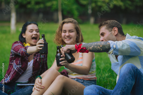 Joyful besties celebrate the occasion in a park. Students have a beer and rest after classes.