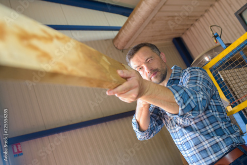 Man checking straightness of piece of wood