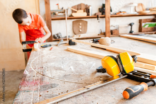 Little talented genius boy works with wood in a carpentry workshop. The concept of learning, hobbies and manual hand work for children