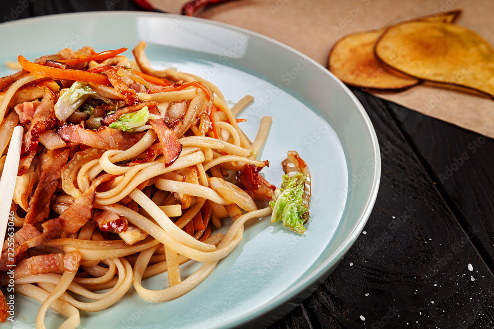 Selective focus on Chinese noodles with chicken and vegetables on dark background. Chinese cuisine, close up view, copy space for text, dark background Selective focus on Chinese noodles with chicken and vegetables on dark background. Chinese cuisine, close up view, copy space for text, dark background