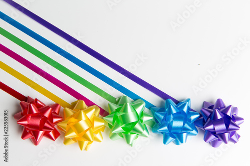 Pink, yellow, red, green, blue and purple gift wrap bows with diagonally placed ribbons top view on white background
