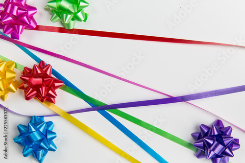 A top view of pink,yellow,red,green,blue and purple gift wrap bows with free lying ribbons  on white background