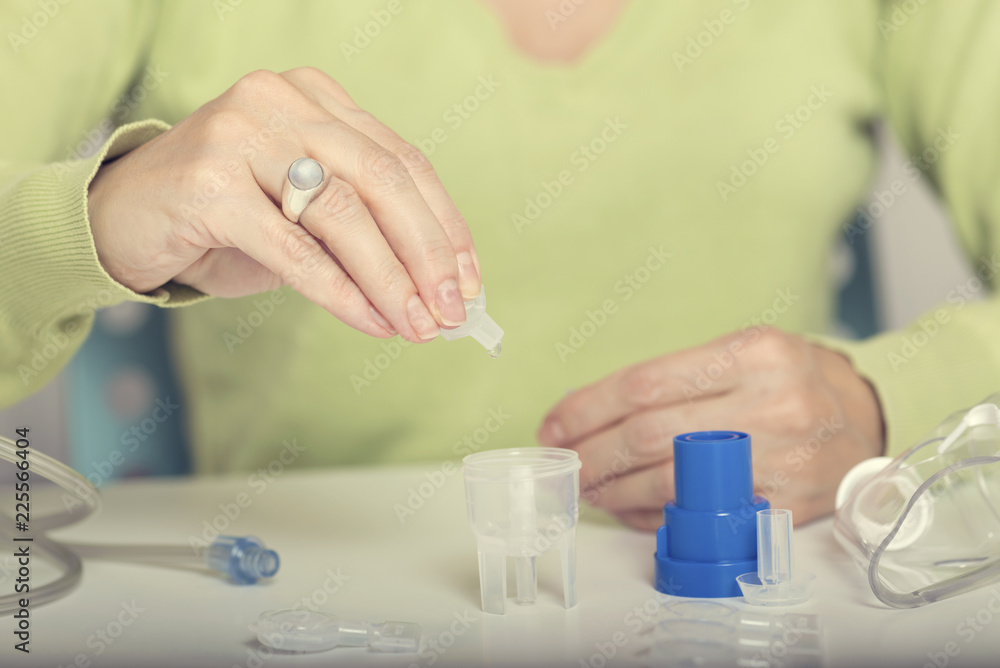 Home treatment. Female hand puts drug in a nebuliser container Home treatment. Female hand puts drug in a nebuliser container