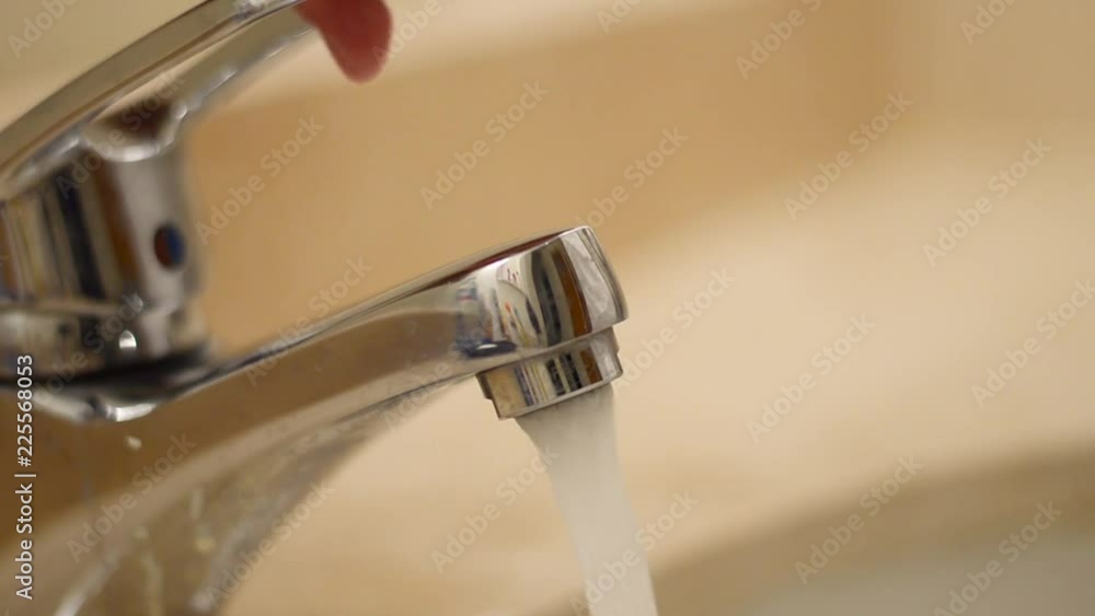 hand opens the water tap, faucet with flowing water in wash sink hand opens the water tap, faucet with flowing water in wash sink