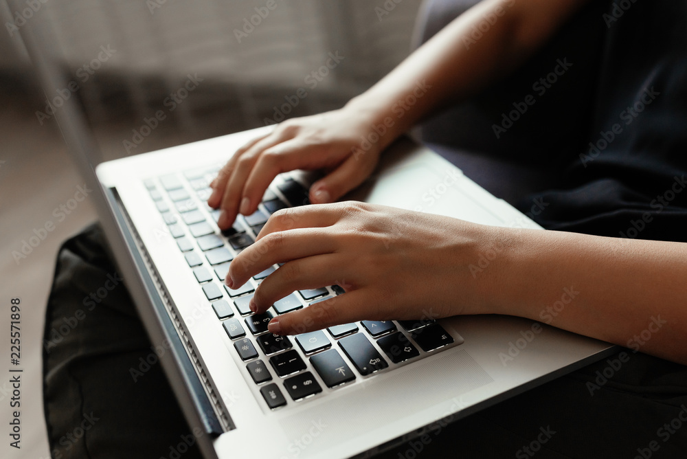 Studying concept. Close-up view of female student in casual clothes typing on laptop`s keyboard, sitting on home. Studying concept. Close-up view of female student in casual clothes typing on laptop`s keyboard, sitting on home.