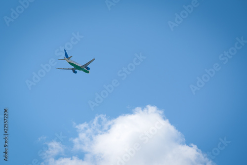 Passenger airplane gain altitude against blue sky and white clouds.