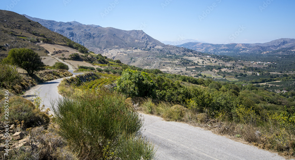 road among green mountains against the blue sky in Crete, Greece