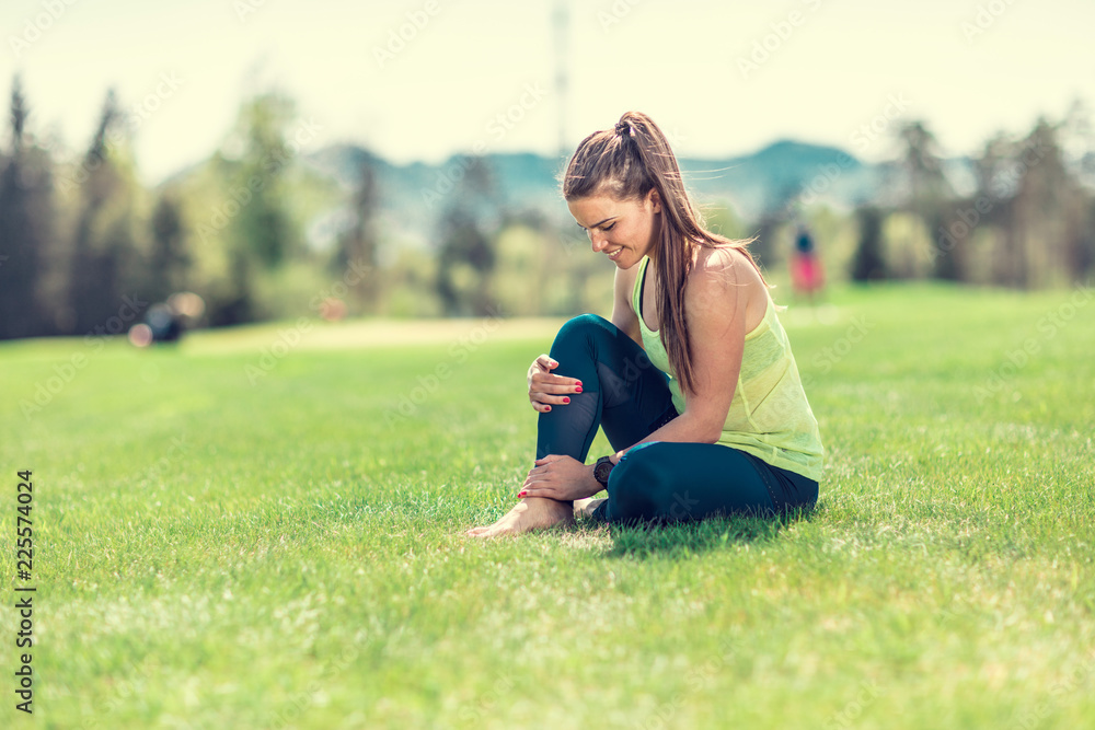 beautiful young sporty brunette relaxing in a park, stretching and looking at her phone beautiful young sporty brunette relaxing in a park, stretching and looking at her phone