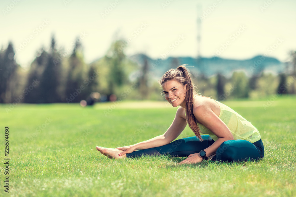beautiful young sporty brunette relaxing in a park, stretching and looking at her phone beautiful young sporty brunette relaxing in a park, stretching and looking at her phone