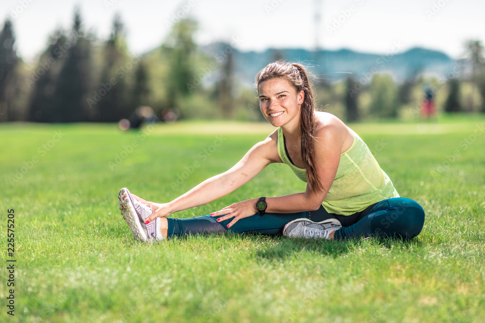 beautiful young sporty brunette relaxing in a park, stretching and looking at her phone beautiful young sporty brunette relaxing in a park, stretching and looking at her phone