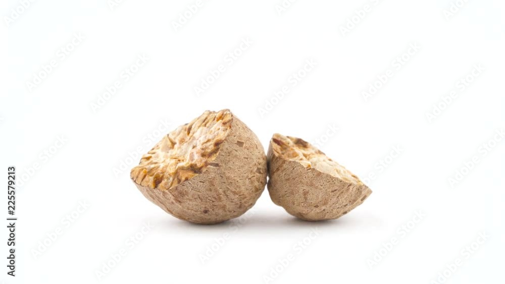 Two cracked parts of nutmeg. Quickly rotating on the turntable isolated on the white background. Close up. Macro. Two cracked parts of nutmeg. Quickly rotating on the turntable isolated on the white background. Close up. Macro.