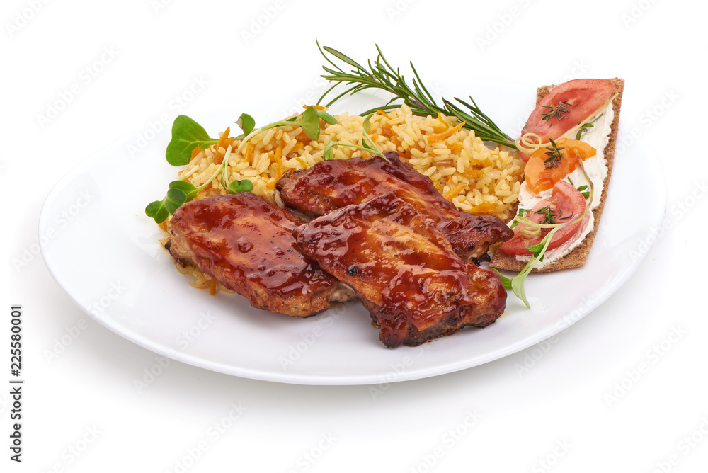 Delicious grilled pork ribs in BBQ sauce with pilaf with herbs and tomatoes, isolated on white background. Close-up. Delicious grilled pork ribs in BBQ sauce with pilaf with herbs and tomatoes, isolated on white background. Close-up.