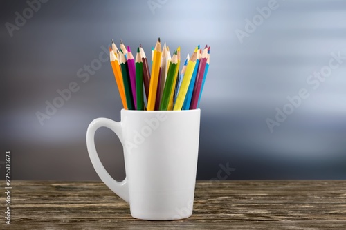 Colorful pencils in jar and red apple