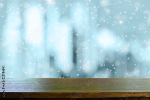 Empty dark tone wooden table with falling snow in nice freezing blue tone bokeh background. for display or montage your products.