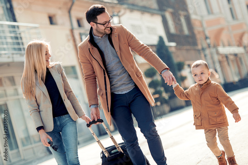 Happy family with luggage in city street