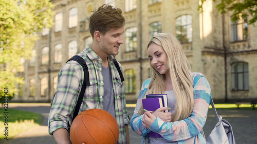 Student holding ball, flirting with pretty girl near university, asking for date