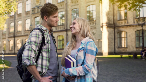 Couple looking at each other and flirting, students at break near college