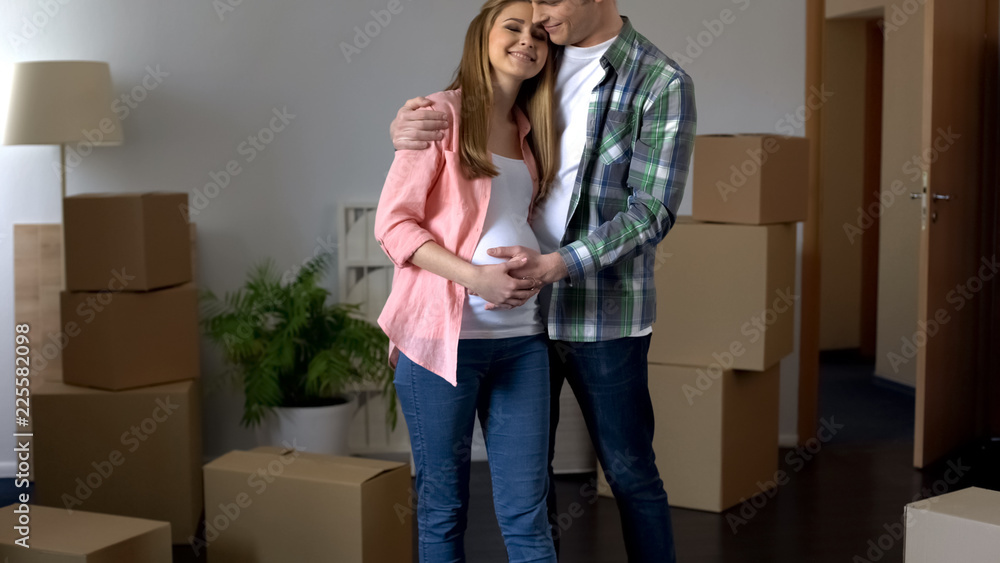 Man embracing pregnant wife in new flat, program of affordable housing for youth Man embracing pregnant wife in new flat, program of affordable housing for youth