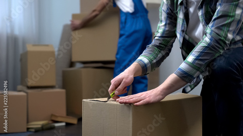 Man unpacking things in new apartment, moving company worker bringing boxes
