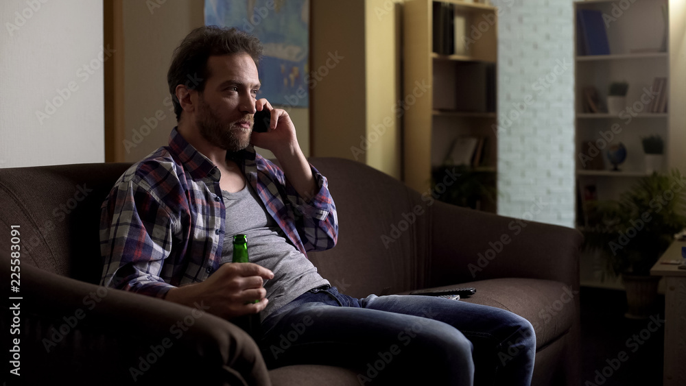 Messy male talking on mobile phone, drinking beer from bottle, frustration