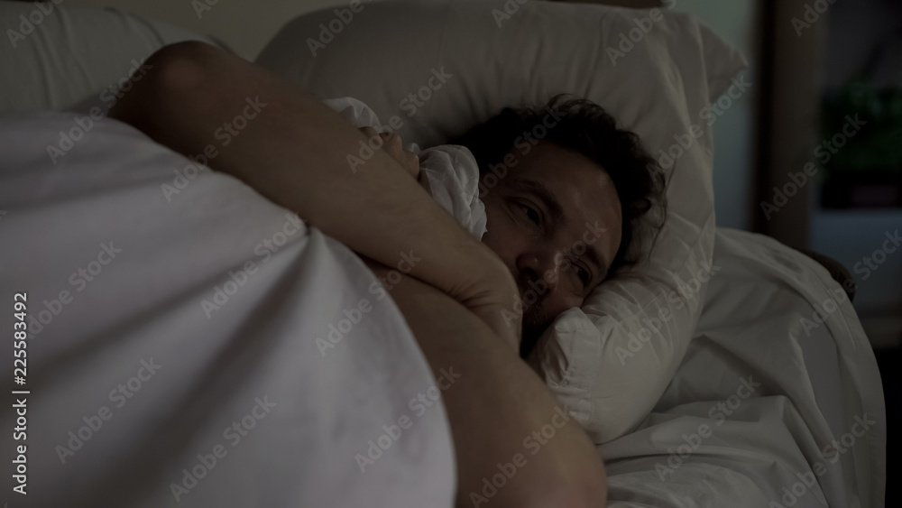 Depressed man lying in bed unable to fall asleep, noisy neighbors, insomnia Depressed man lying in bed unable to fall asleep, noisy neighbors, insomnia