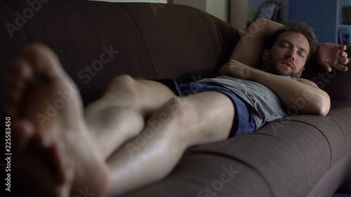 Tired male lying on sofa in boxers, dozing in front of TV, weekend, single life