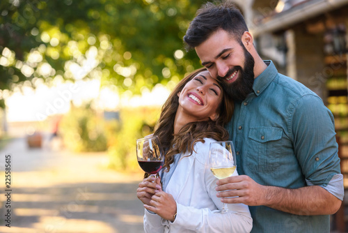 Portrait of young smiling man and woman tasting wine at winery vineyard - Young people enjoying harvest time together. Romantic love. photo